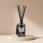 Aroma Sense 150ml blue glass reed diffuser with black reeds on a travertine stand